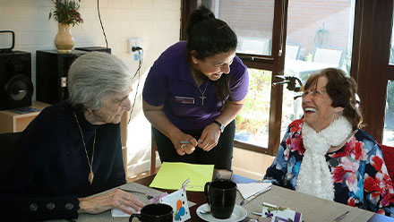 Caring staff member sharing a light-hearted moment, bringing laughter to residents.