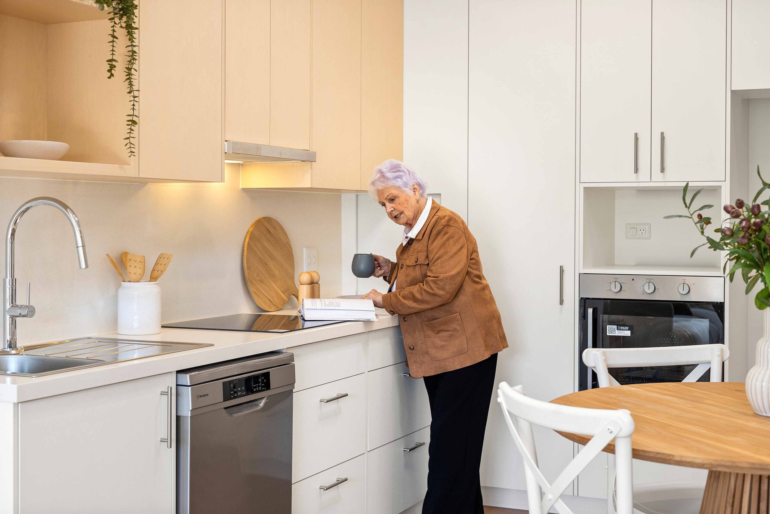 Woman reading cook book within Warrigal Lake South villa kitchen