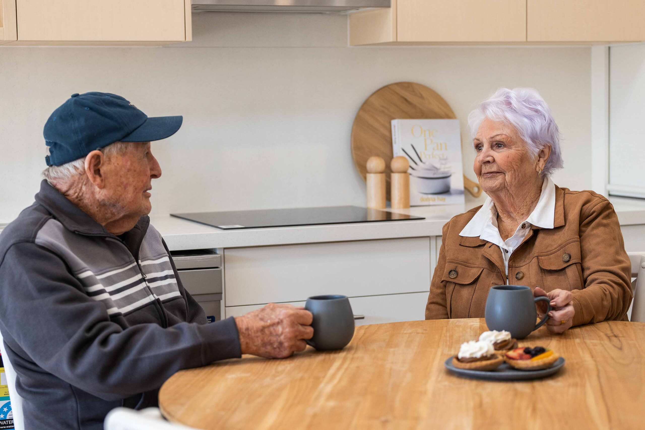 Man and woman sit at table in Warrigal Lake South villa kitchen