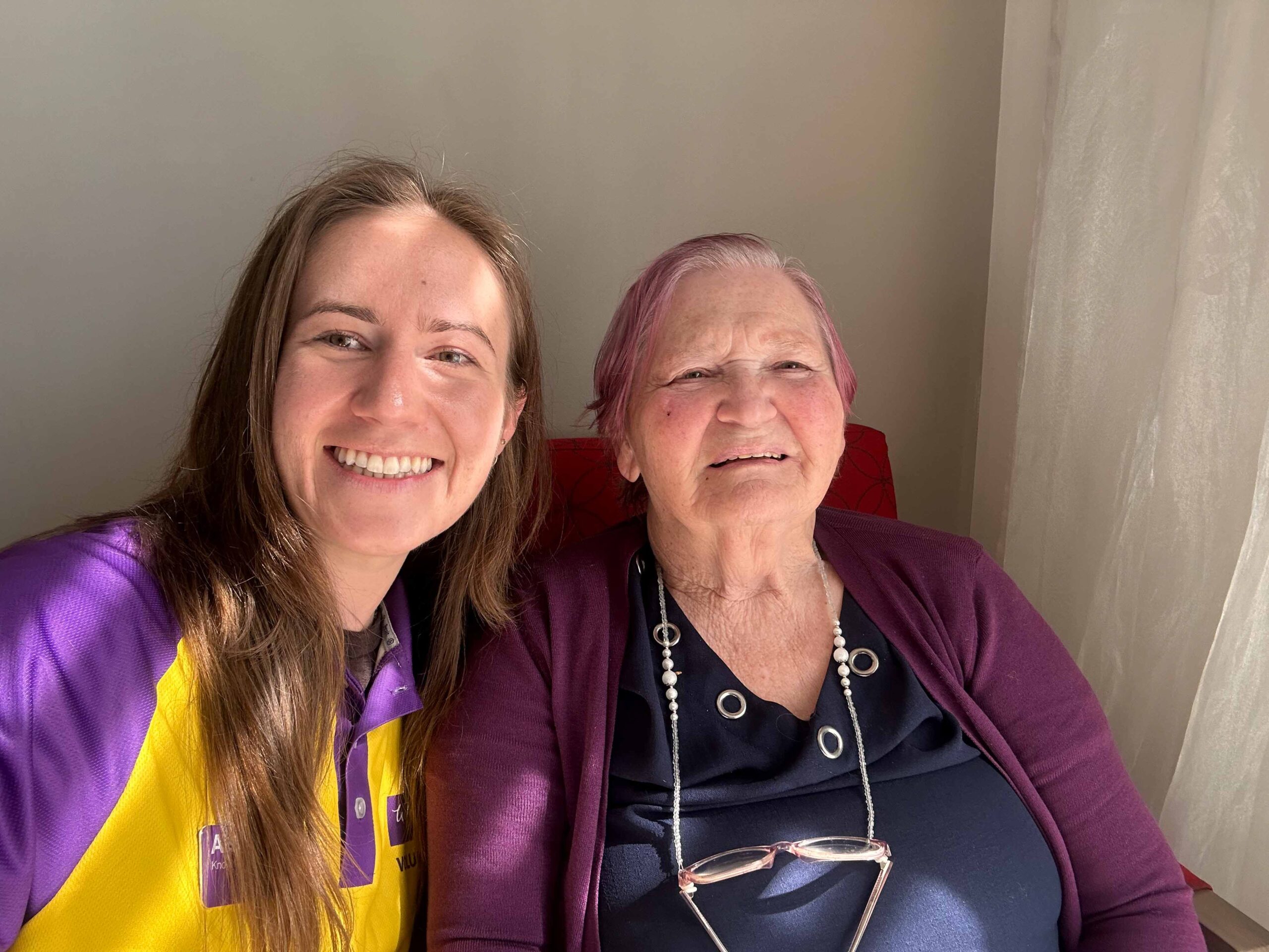 Young volunteer smiling next to smiling resident