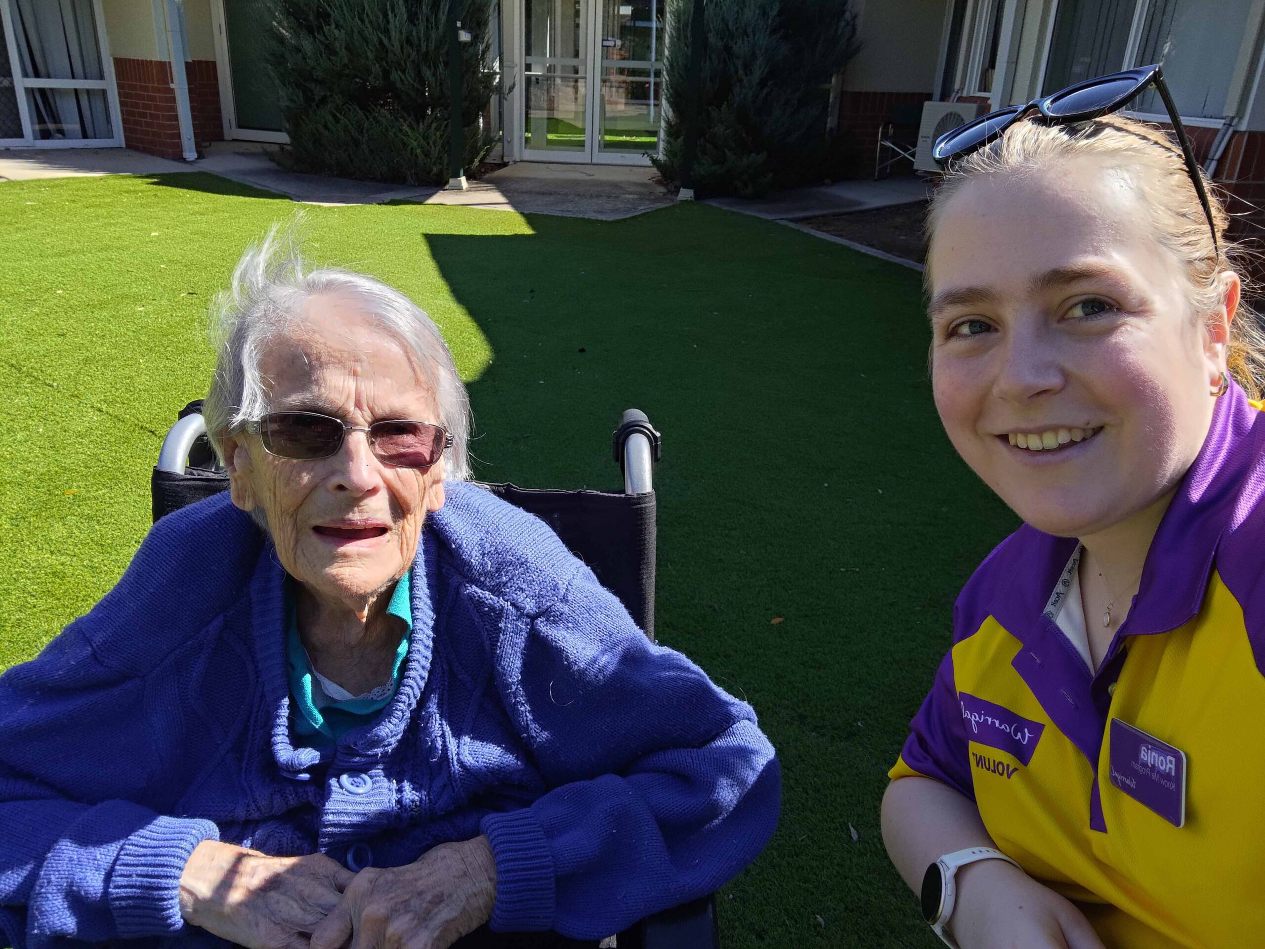 Young volunteer smiling with older person